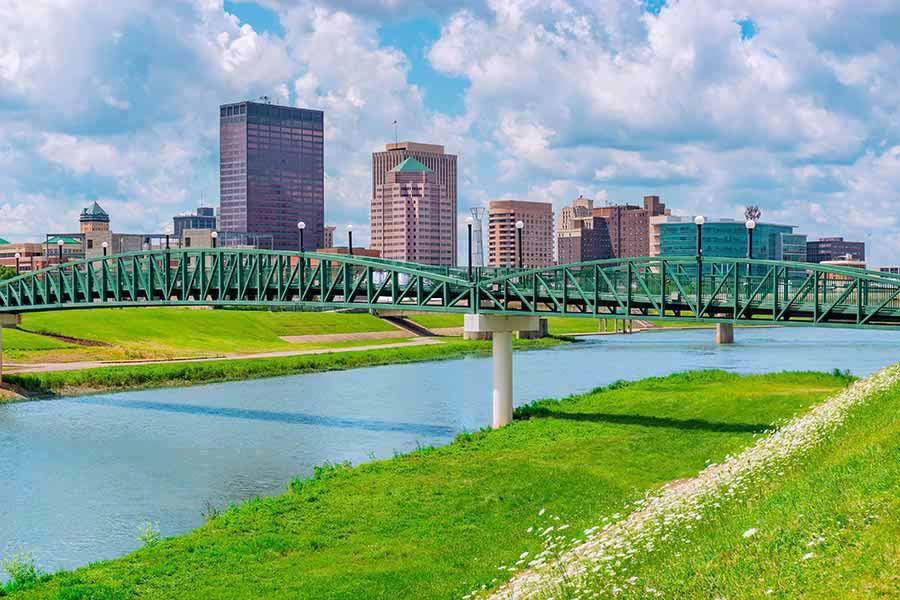 Homepage - View of Dayton, Ohio From a Distance, the Miami River and Green Grass in the Foreground, White Clouds Overhead